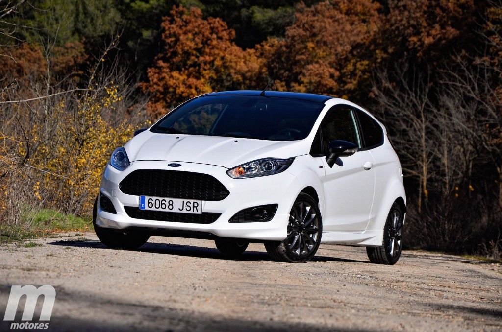 Los 12 mejores coches de segunda mano por menos de 10.000 euros 12 Ford Fiesta 1.0 EcoBoost de color blanco con lunas tintadas estacionado en camino de tierra, de fondo paisaje otoñal.