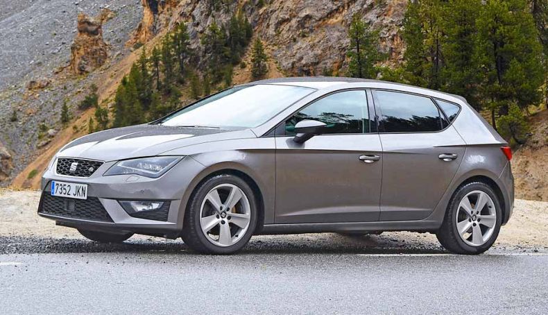 Seat León 2.0 TDI 150 CV color gris estacionado en la carretera visto de lado.