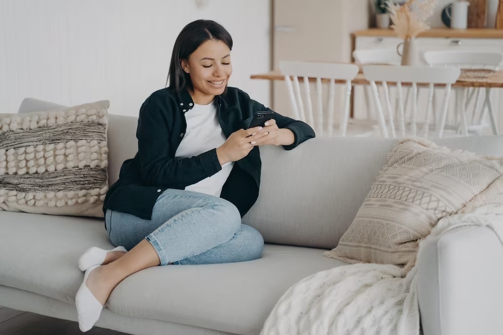 happy woman relaxing with mobile phone reading messages comfortable couch living room 95891 7894 tra