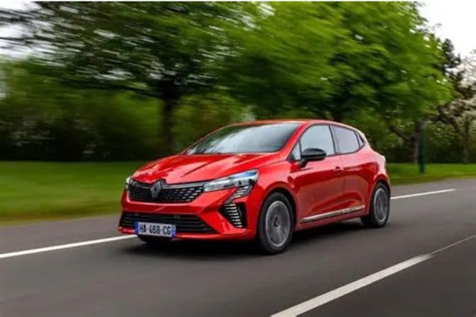 Los 16 mejores coches de segunda mano para comprar en 2026 4 Renault Clio V rojo circulando por una carretera con árboles verdes a ambos lados