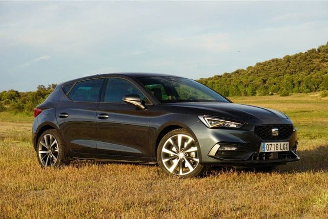 Los 16 mejores coches de segunda mano para comprar en 2026 5 SEAT León gris oscuro aparcado en un campo de hierba seca con colinas al fondo