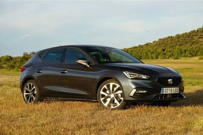Los 16 mejores coches de segunda mano para comprar en 2026 5 SEAT León gris oscuro aparcado en un campo de hierba seca con colinas al fondo