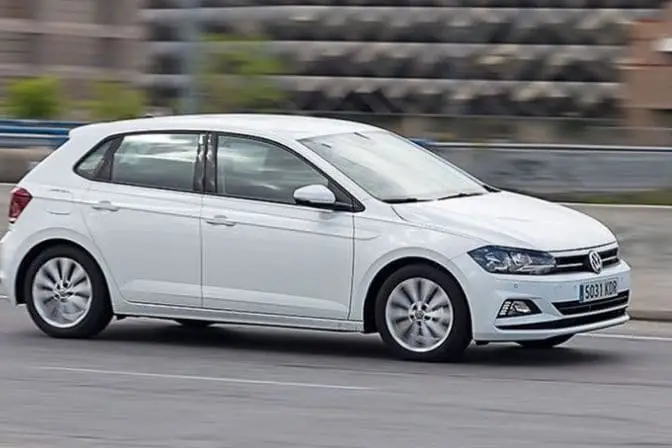 Los 16 mejores coches de segunda mano para comprar en 2026 2 Volkswagen Polo blanco de sexta generación circulando por una carretera urbana a velocidad