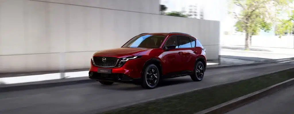 Los 8 SUV más fiables en 2026. Cuál deberías comprar 2 Mazda CX5 de color rojo circulando por espacio urbano.