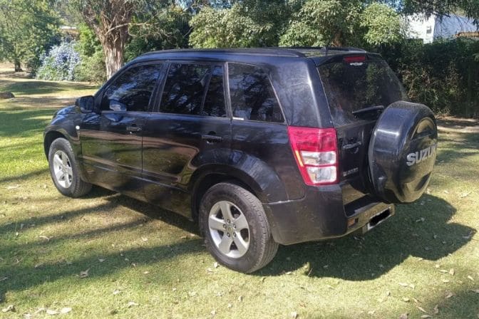 Los mejores 4x4 baratos para comprar a un particular en 2026 2 Suzuki Grand Vitara II negro visto desde la parte trasera, aparcado sobre una zona de césped rodeada de árboles