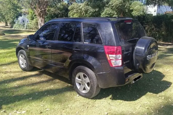 Los mejores 4x4 baratos para comprar a un particular en 2026 2 Suzuki Grand Vitara II negro visto desde la parte trasera, aparcado sobre una zona de césped rodeada de árboles
