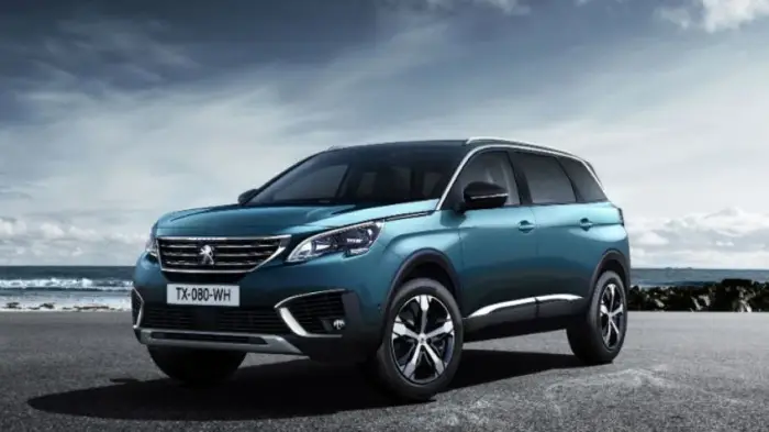 Los 12 mejores coches familiares de segunda mano para 2026 8 Peugeot 5008 verde azulado parado frente al mar bajo un cielo nublado