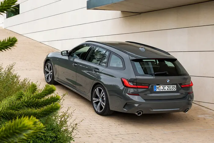 Los 12 mejores coches familiares de segunda mano para 2026 10 BMW Serie 3 Touring gris oscuro visto desde atrás junto a un edificio, con el portón y los escapes a la vista