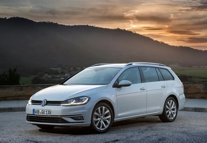 Los 12 mejores coches familiares de segunda mano para 2026 2 Volkswagen Golf Variant blanco aparcado en un mirador al atardecer, con montañas al fondo