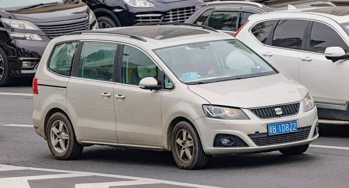 Los 24 mejores coches familiares de 7 plazas de ocasión 1 Seat Alhambra Mk2 beige circulando entre tráfico urbano, visto de tres cuartos delantero con otros coches alrededor