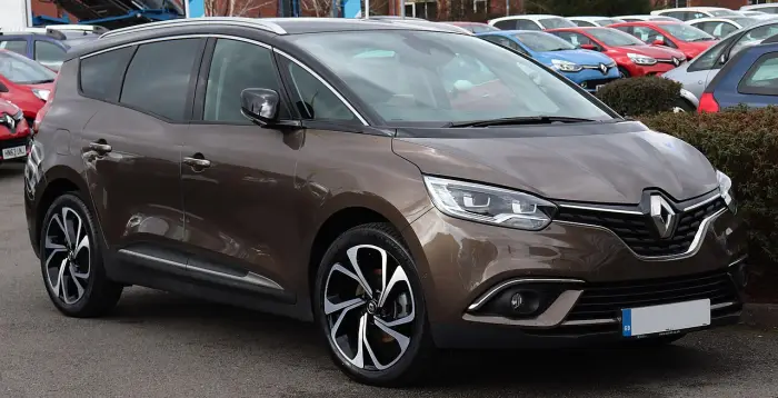 Los 24 mejores coches familiares de 7 plazas de ocasión 6 Renault Grand Scénic IV marrón con llantas bicolor de gran diámetro, aparcado ante una hilera de coches usados