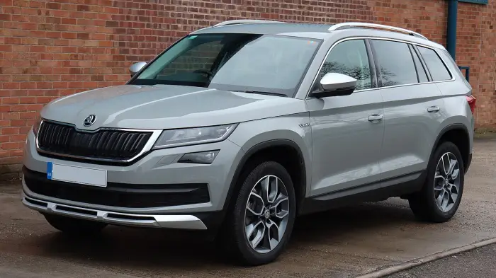Los 24 mejores coches familiares de 7 plazas de ocasión 10 Skoda Kodiaq Scout gris claro con protecciones de bajos, aparcado de tres cuartos delantero ante un muro de ladrillo
