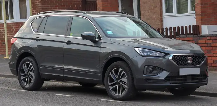 Los 24 mejores coches familiares de 7 plazas de ocasión 11 Seat Tarraco gris antracita aparcado en una calle residencial, de tres cuartos delantero ante una casa de ladrillo