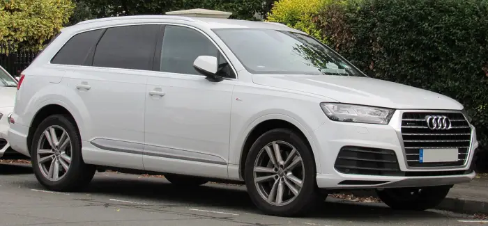 Los 24 mejores coches familiares de 7 plazas de ocasión 18 Audi Q7 4M blanco aparcado junto a un seto y otros coches, visto casi de perfil con las llantas en primer plano