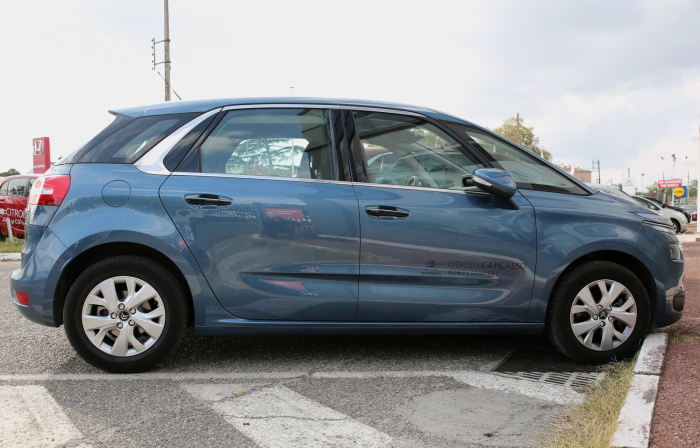 Los 21 mejores monovolúmenes de segunda mano para 2026 3 Citroën C4 Picasso azul de perfil en un concesionario, con rotulación del modelo en las puertas