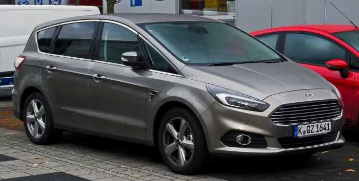 Los 21 mejores monovolúmenes de segunda mano para 2026 8 Ford S-Max gris arena de tres cuartos delantero en un concesionario, con hojas secas en el suelo