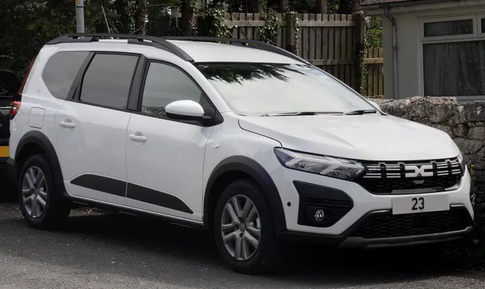 Los 21 mejores monovolúmenes de segunda mano para 2026 11 Dacia Jogger blanco con barras de techo, de tres cuartos delantero junto a un muro de piedra